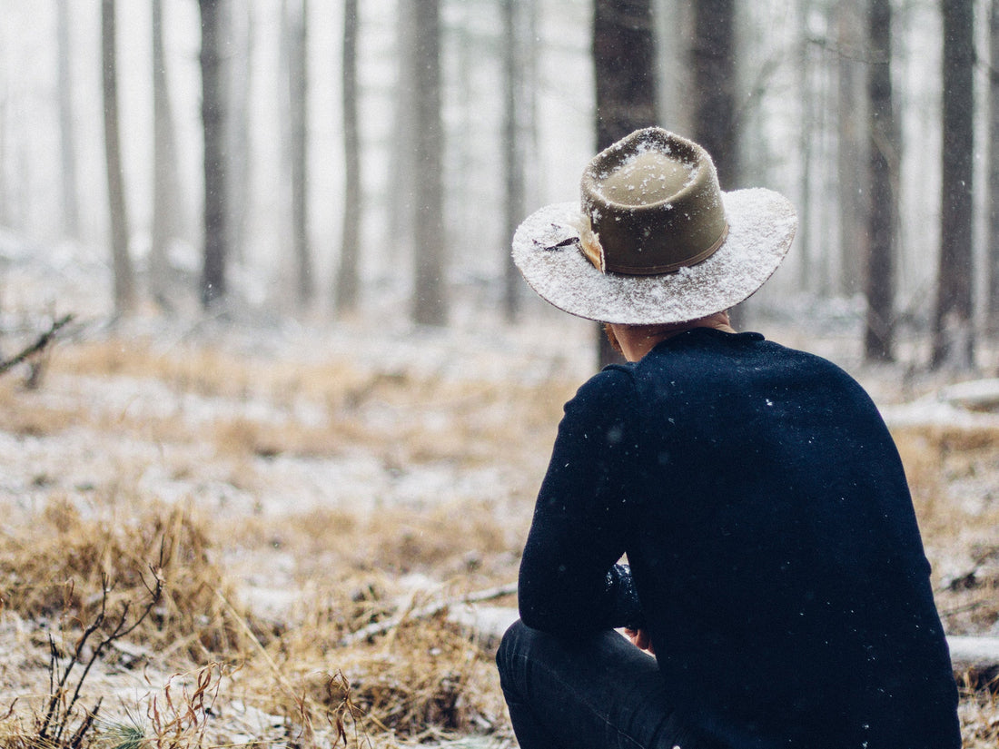 Person sitting in snowy forest comparing microfleece vs fleece for warmth during colder weather