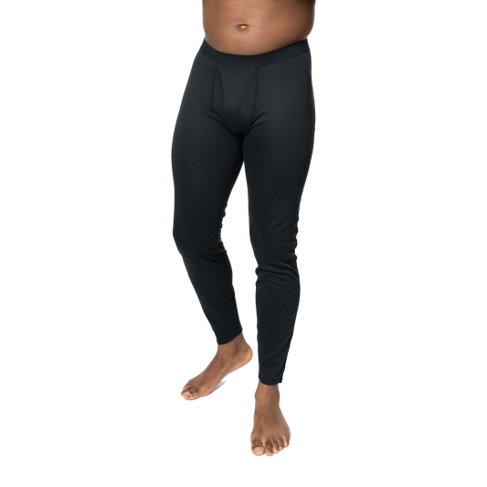 Polarmax black base layer pants for men modeled on a standing man with bare feet against black background