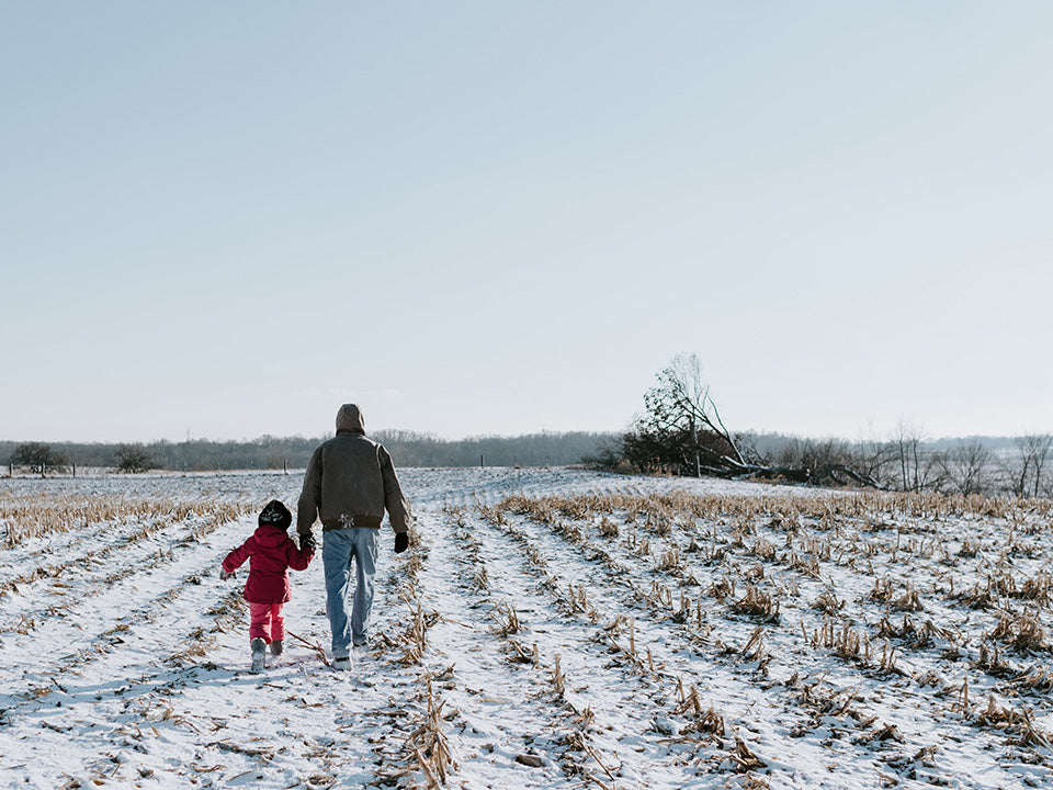 Image by Kelly Sikkema UnSplash - Adult and Child walking on a farm field in the winter
