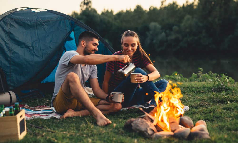 Couple enjoying a campfire while wearing the best base layers for fall camping