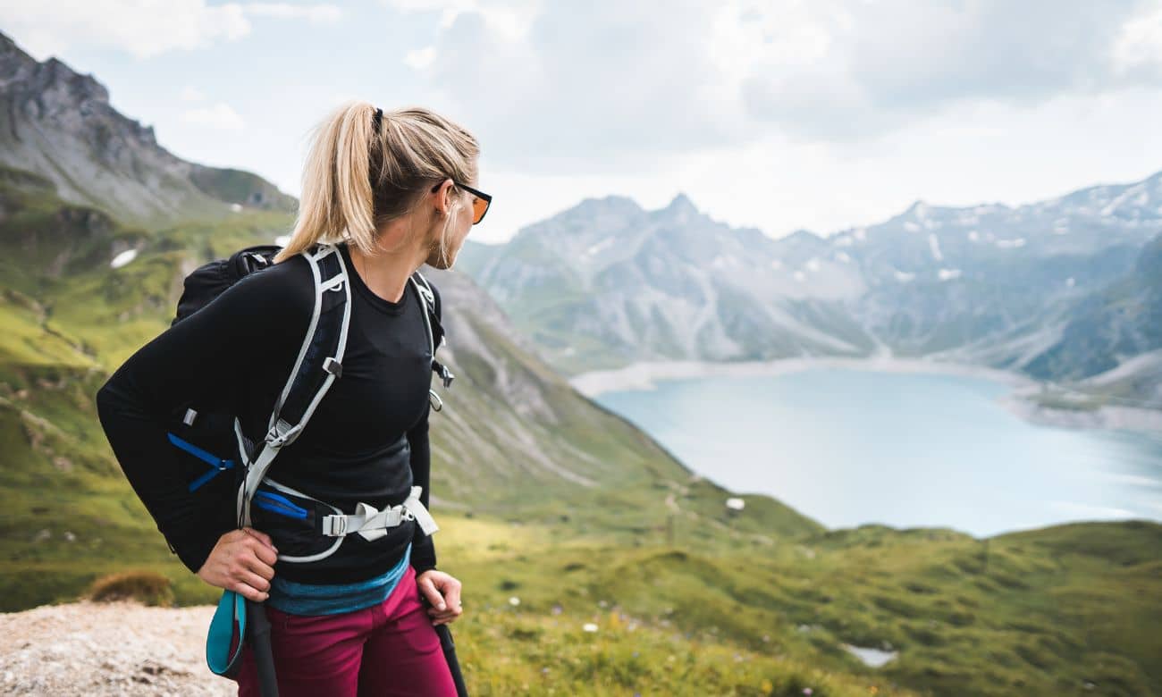 Hiker looking at scenic mountain view while dressed in outdoor gear showcasing the difference between microfleece and fleece